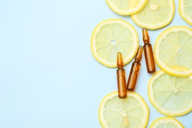 Skincare ampoules with vitamin C and slices of lemon on light blue background, flat lay. Space for text