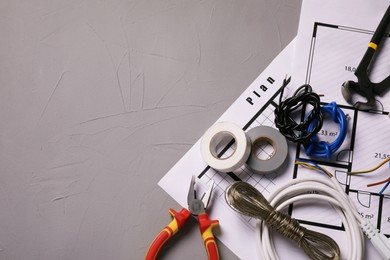 Photo of Different wires, electrician's tools and schemes on grey table, flat lay. Space for text