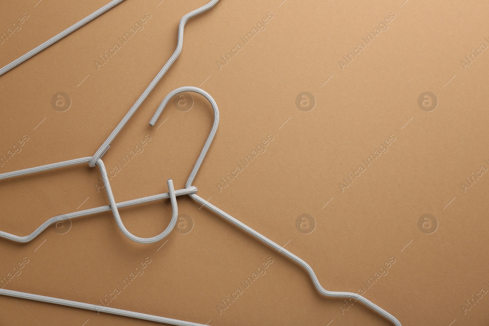 Photo of Empty hangers on brown background, top view. Space for text