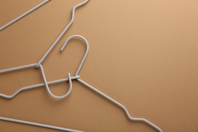 Empty hangers on brown background, top view. Space for text