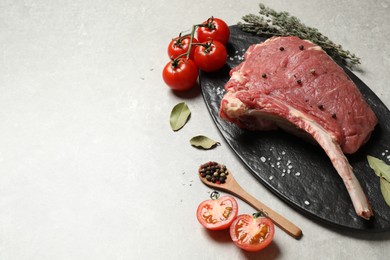 Photo of Raw rib with herbs, spices and tomatoes on grey table, flat lay. Space for text