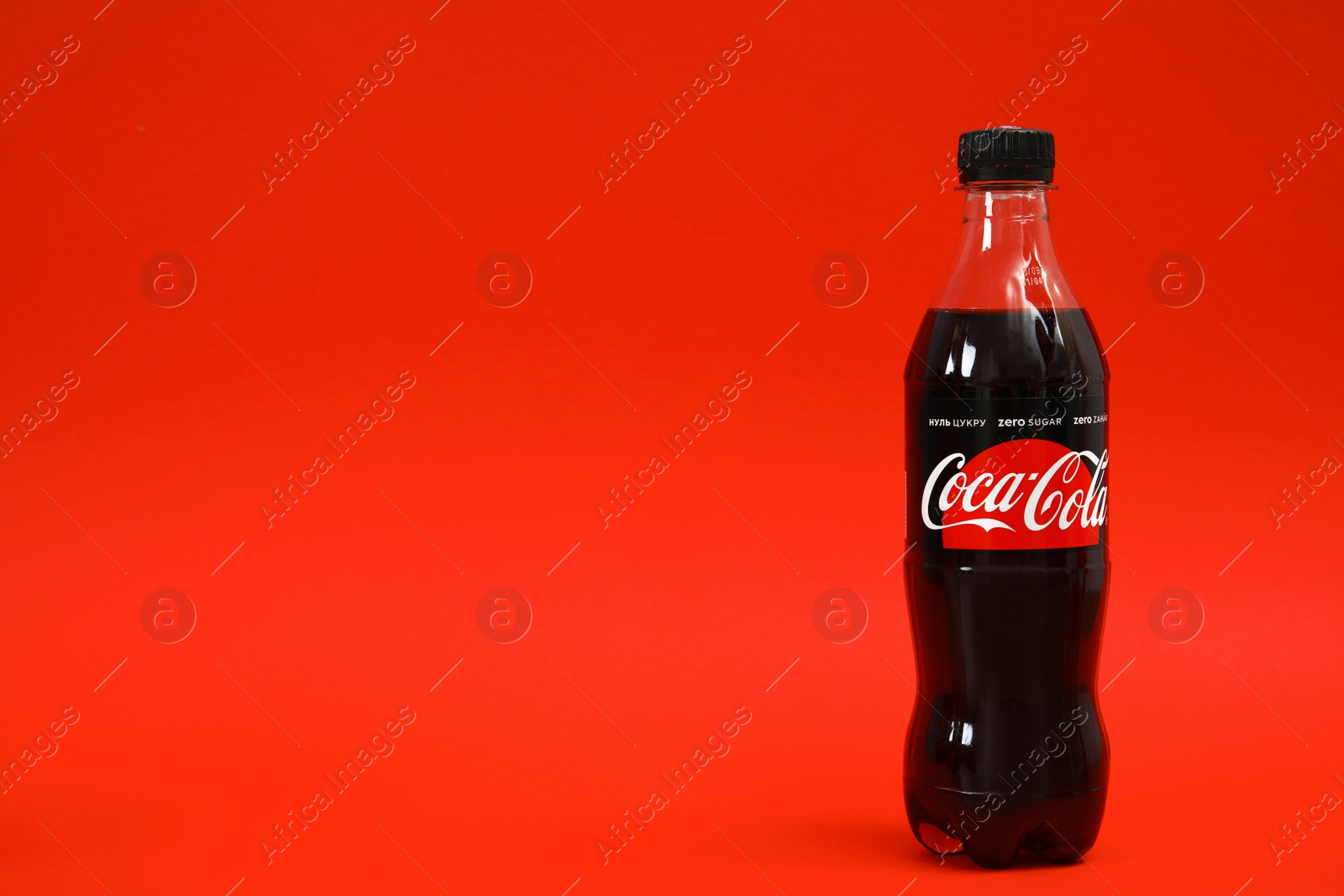 Photo of MYKOLAIV, UKRAINE - NOVEMBER 14, 2018: Bottle of Coca-Cola on color background. Space for text