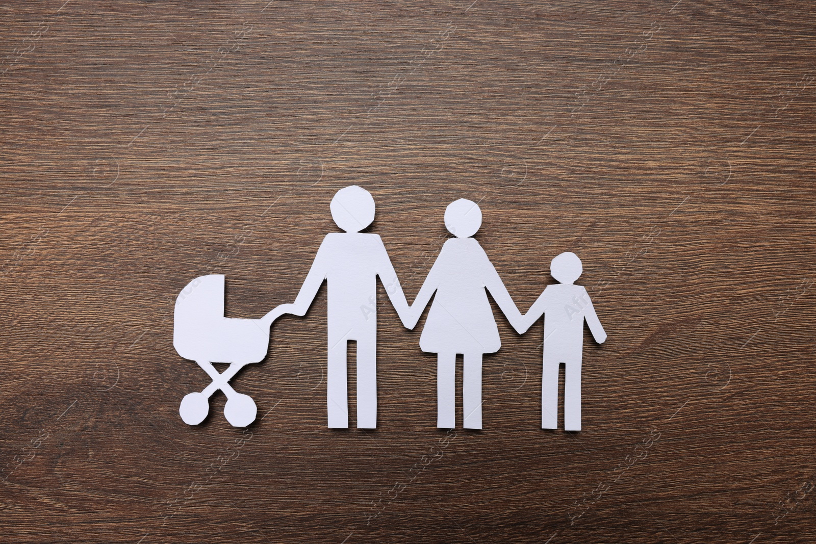 Photo of Paper family cutout on wooden background, top view. Insurance concept