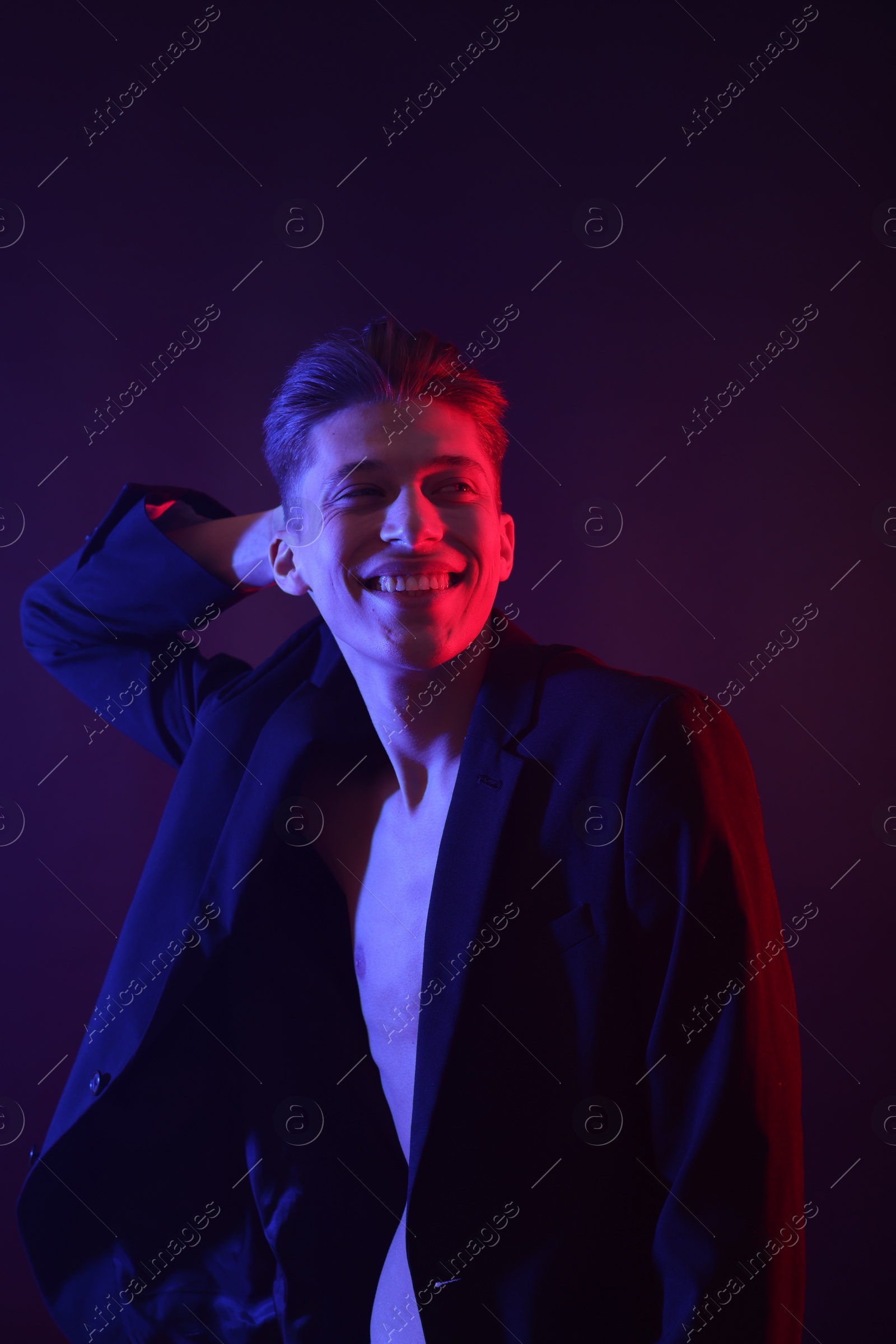 Photo of Sexy young man on dark background in neon lights