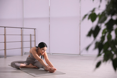 Young woman stretching leg in yoga studio. Janu Sirsasana pose variation