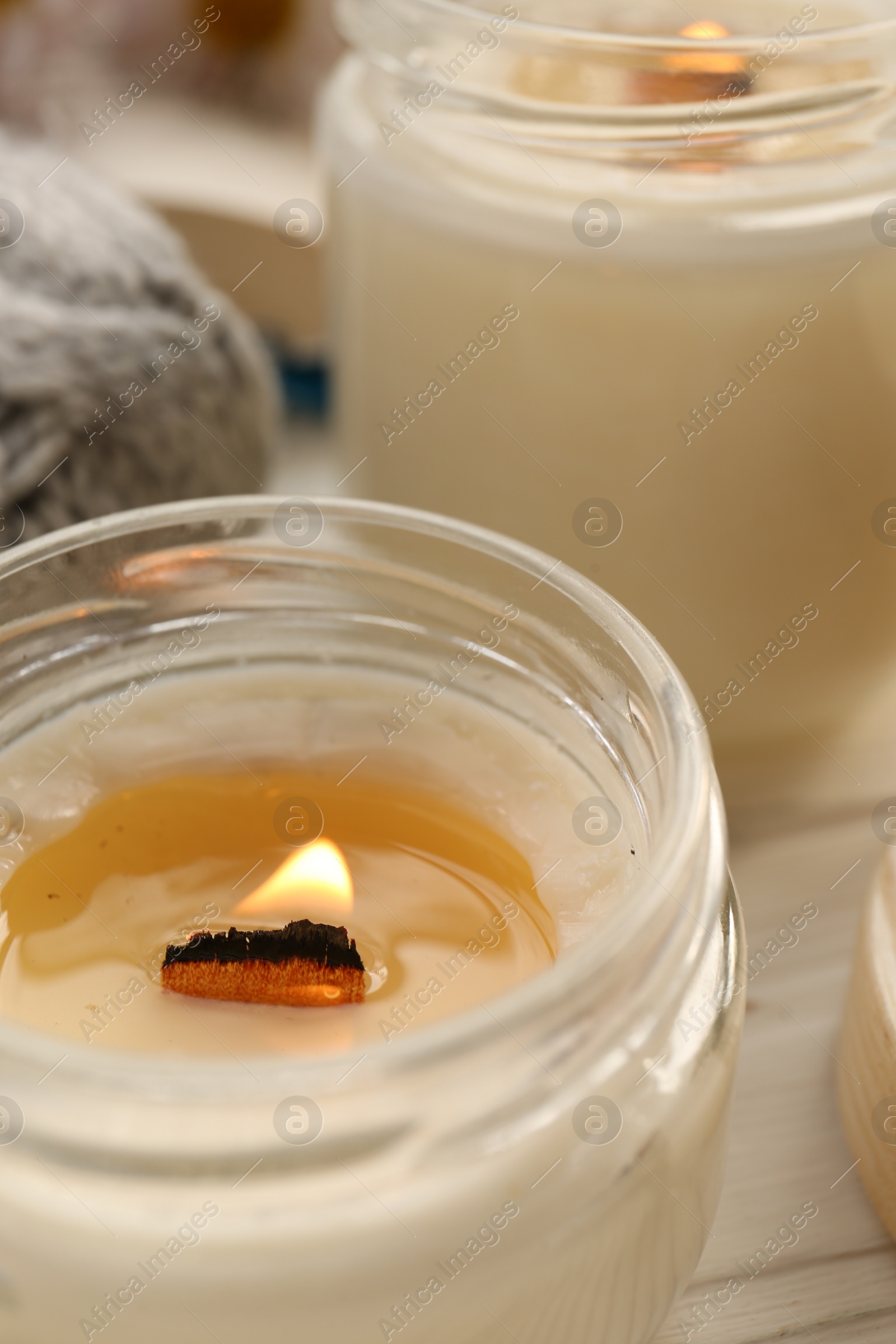 Photo of Burning scented candles on white wooden table, closeup