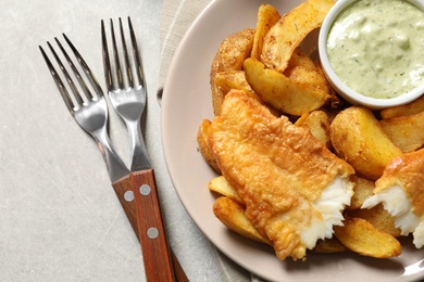 Photo of Plate with British Traditional Fish and potato chips on grey background