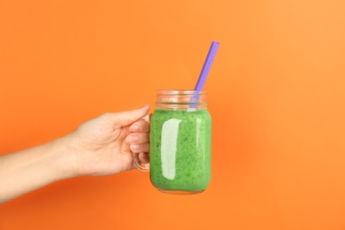 Photo of Woman holding mason jar with delicious smoothie on color background