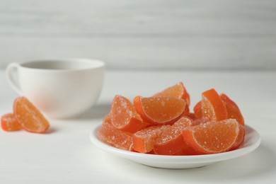 Photo of Tasty orange jelly candies on white table. Space for text