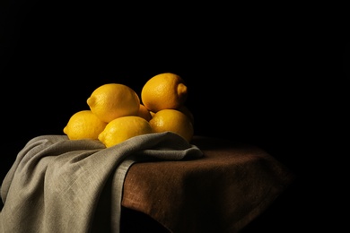 Photo of Ripe whole lemons on table against dark background