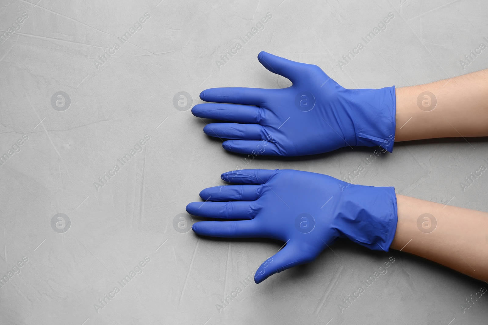 Photo of Person in medical gloves on light grey background, closeup of hands. Space for text