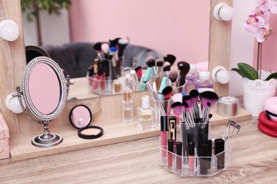 Photo of Organizer with cosmetic products for makeup on table near mirror. Space for text