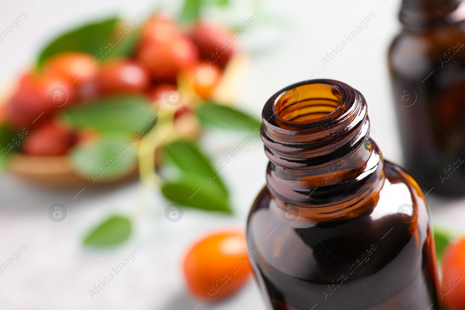 Photo of Glass bottle with jojoba oil on blurred background, closeup. Space for text