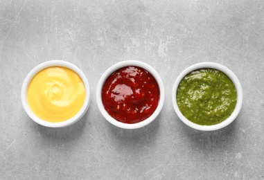 Photo of Set of different delicious sauces on grey table, top view