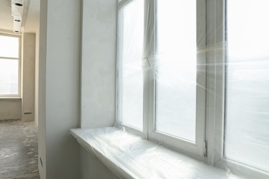 Big windows covered with plastic film in room