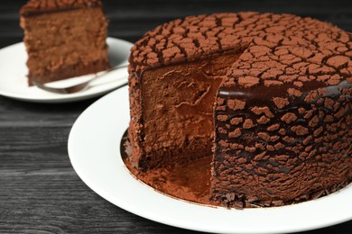 Delicious chocolate truffle cake on black wooden table, closeup