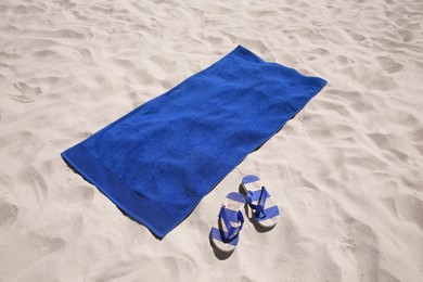 Photo of Flip flops and blue beach towel on sand