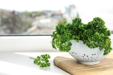 Photo of Colander with fresh green parsley on window sill indoors, space for text
