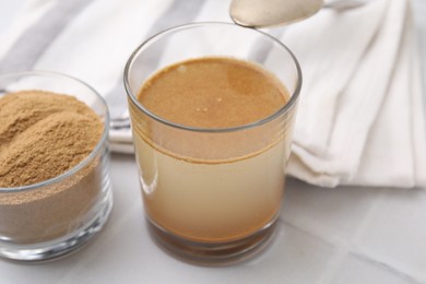 Soluble fiber with water in glass and powder on white table, closeup