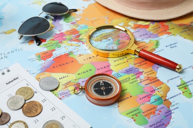 Photo of Different travel accessories on world map, closeup. Planning summer vacation trip