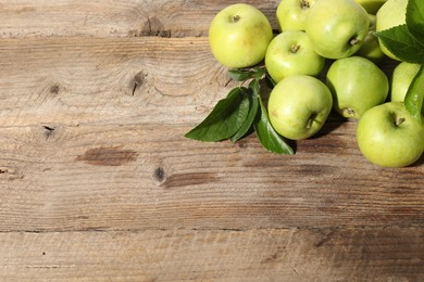 Photo of Many fresh apples and leaves on wooden table, top view. Space for text