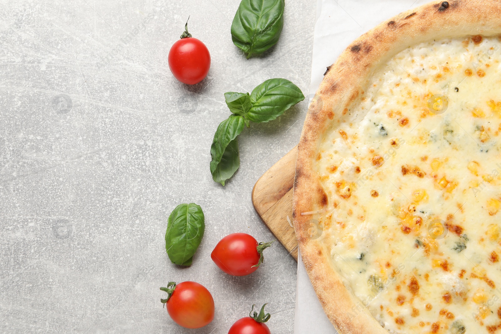 Photo of Delicious cheese pizza, basil and tomatoes on light grey table, flat lay. Space for text