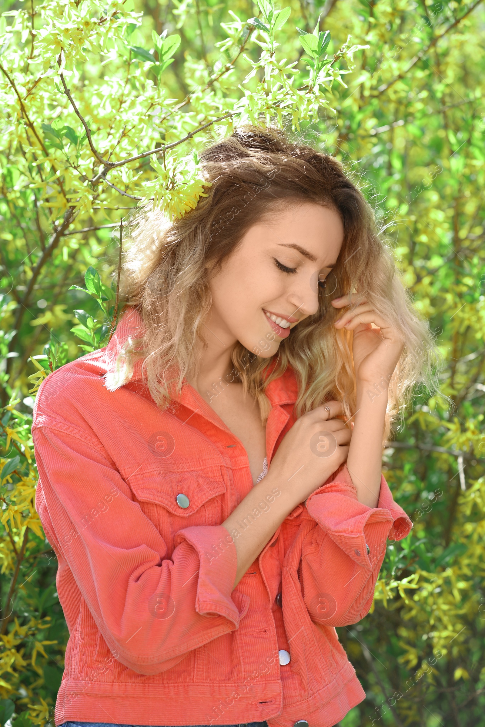 Photo of Attractive young woman posing near blossoming bush on sunny spring day