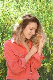 Attractive young woman posing near blossoming bush on sunny spring day