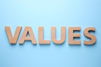 Photo of Word VALUES made of wooden letters on light blue background, flat lay