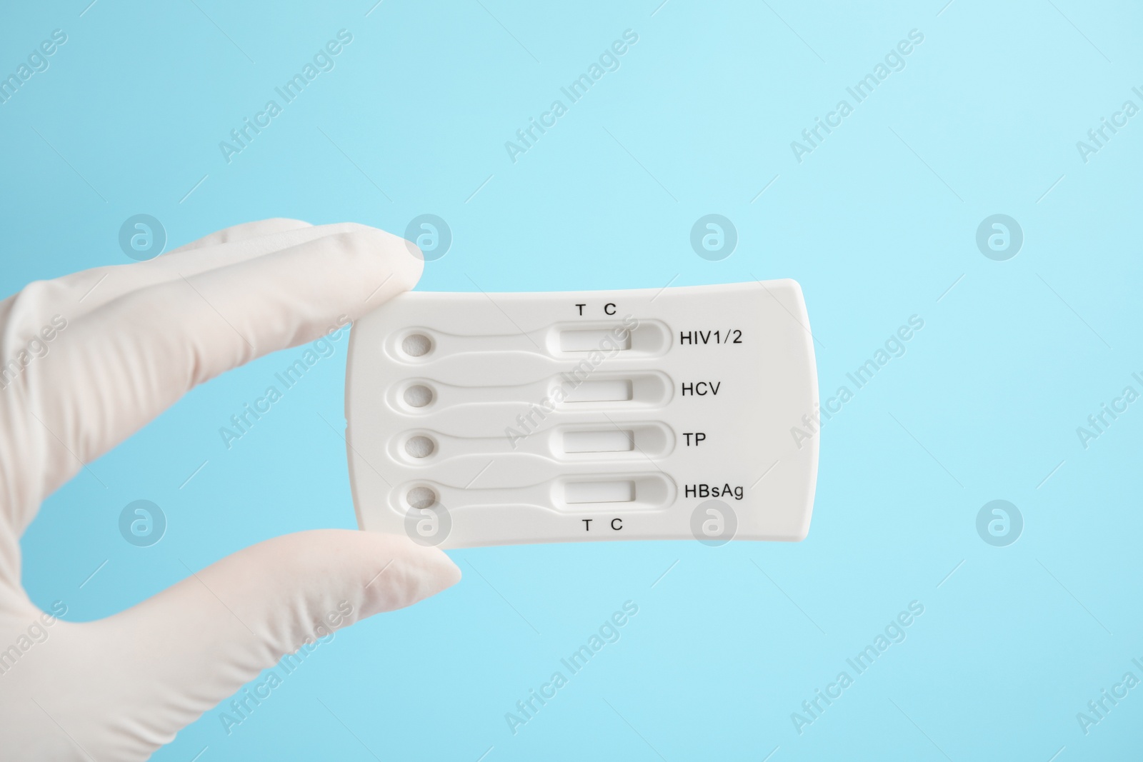 Photo of Doctor holding disposable express test for hepatitis on light blue background, closeup