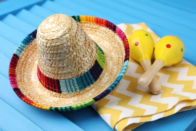 Mexican sombrero hat, towel and maracas on blue wooden surface