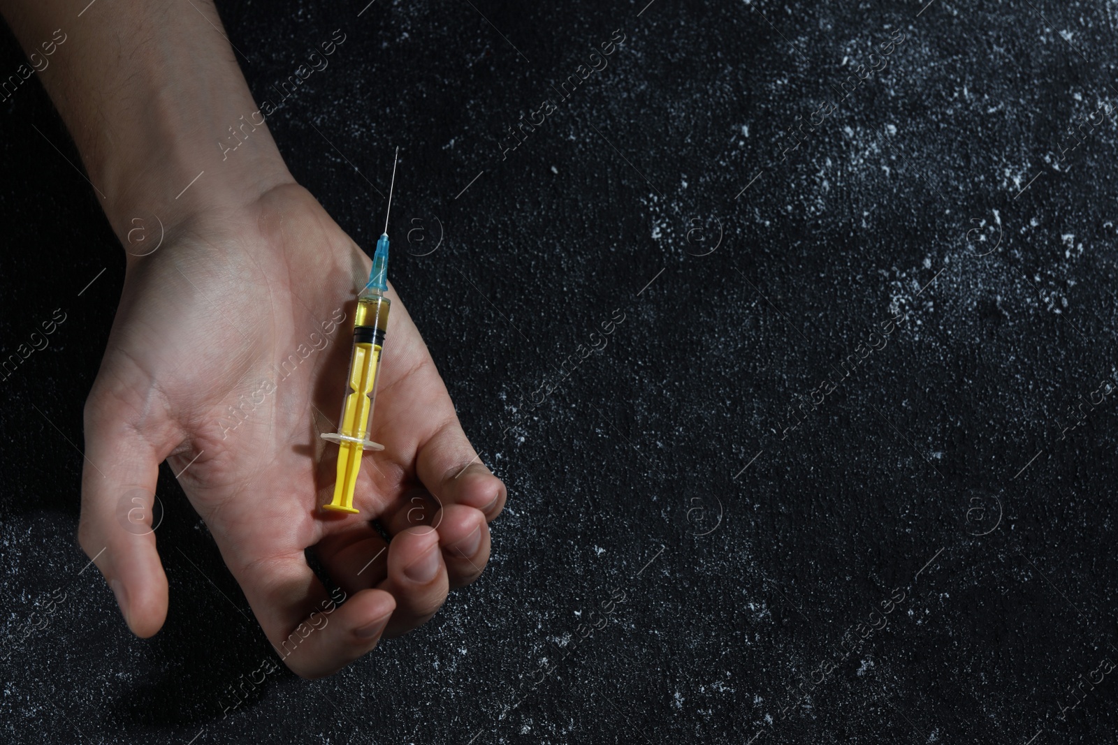 Photo of Drug addiction. Man with syringe on black textured table, top view and space for text
