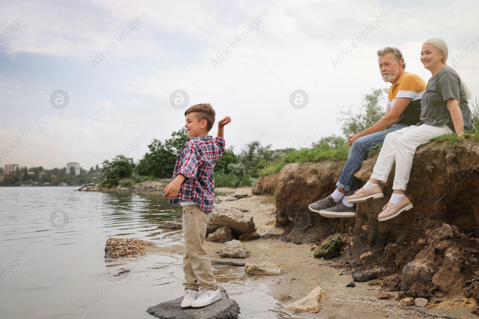 Photo of Cute little boy and grandparents spending time together near river