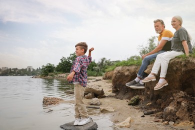 Photo of Cute little boy and grandparents spending time together near river