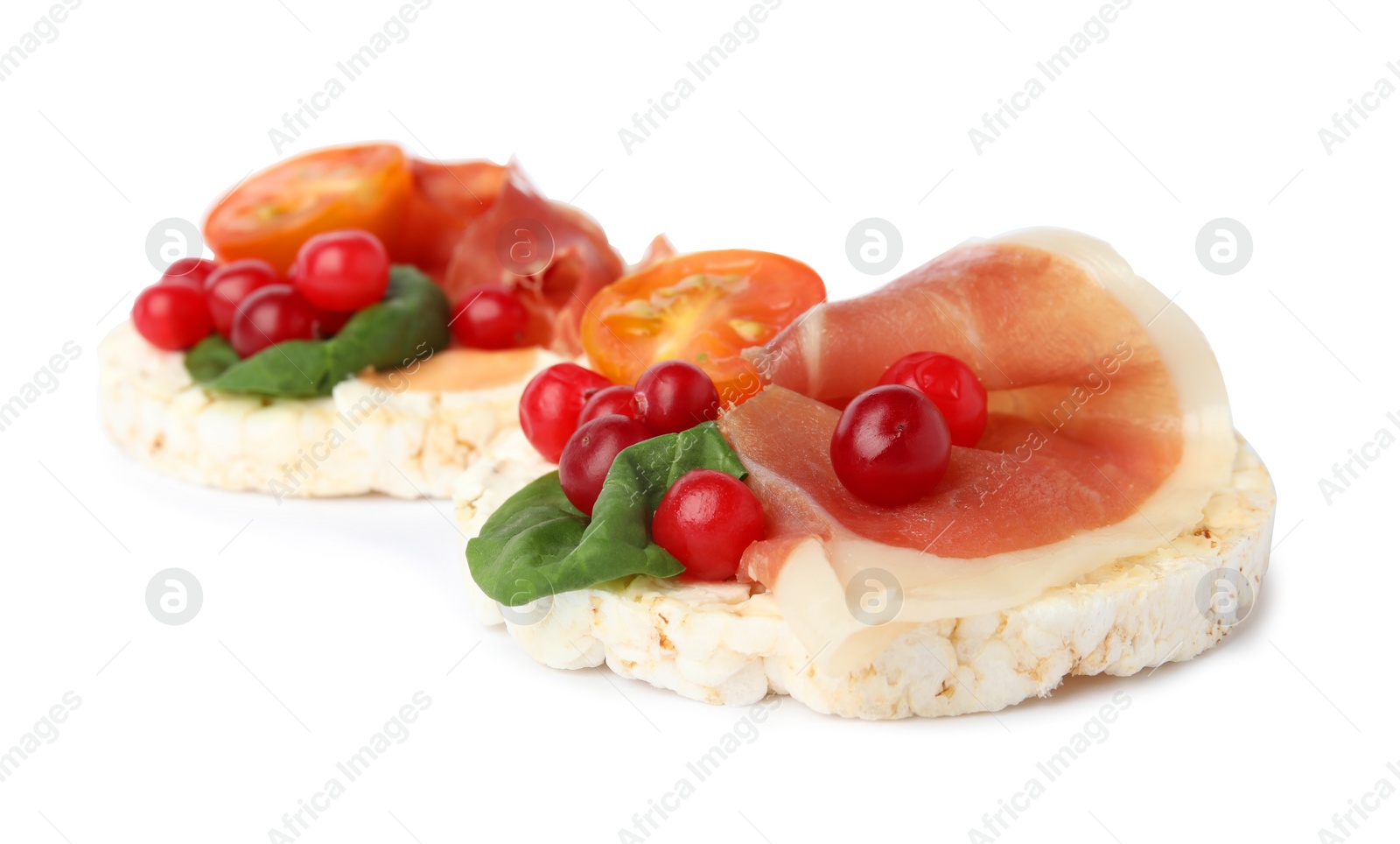 Photo of Puffed rice cakes with prosciutto, berries and tomato isolated on white