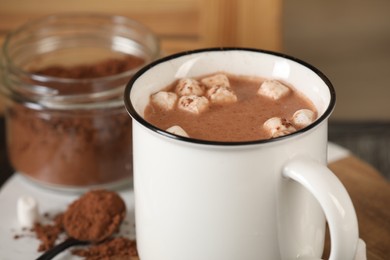 Cup of aromatic hot chocolate with marshmallows and cocoa powder on table, closeup