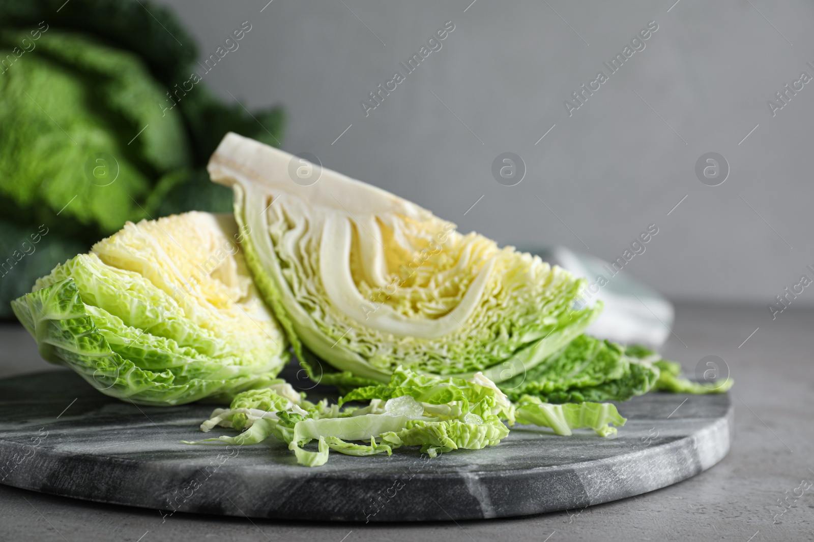 Photo of Cut fresh savoy cabbage on grey table, closeup