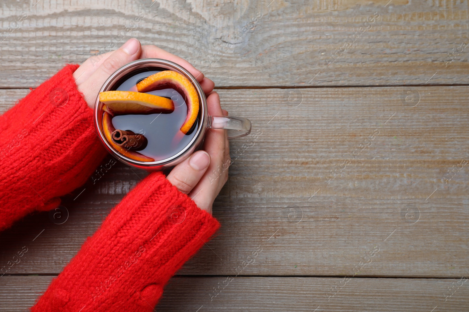 Photo of Woman with cup of mulled wine at wooden table, top view. Space for text