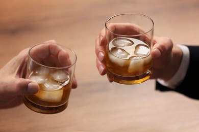 Photo of Men with glasses of whiskey at wooden table, closeup