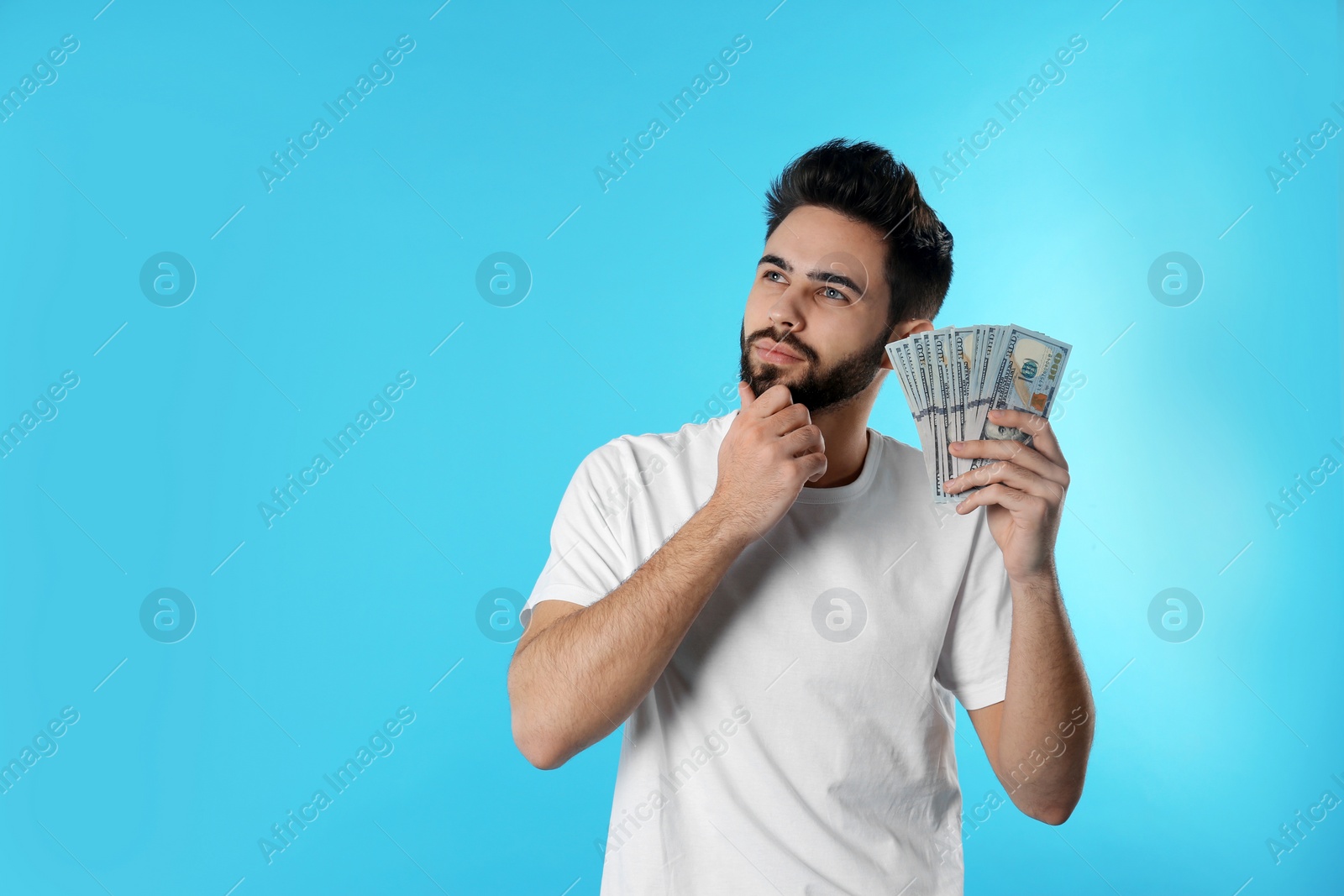 Photo of Portrait of thoughtful young man with money on color background. Space for text