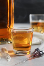 Alcohol and drug addiction. Whiskey in glass, syringes and cocaine on white table