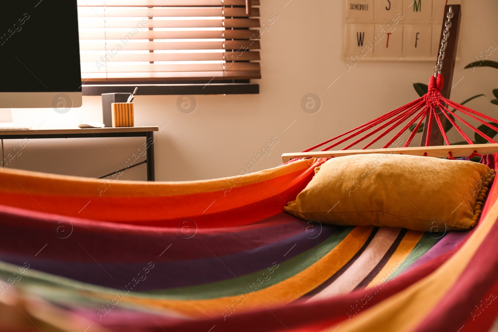 Photo of Colorful hammock with soft pillow indoors, closeup