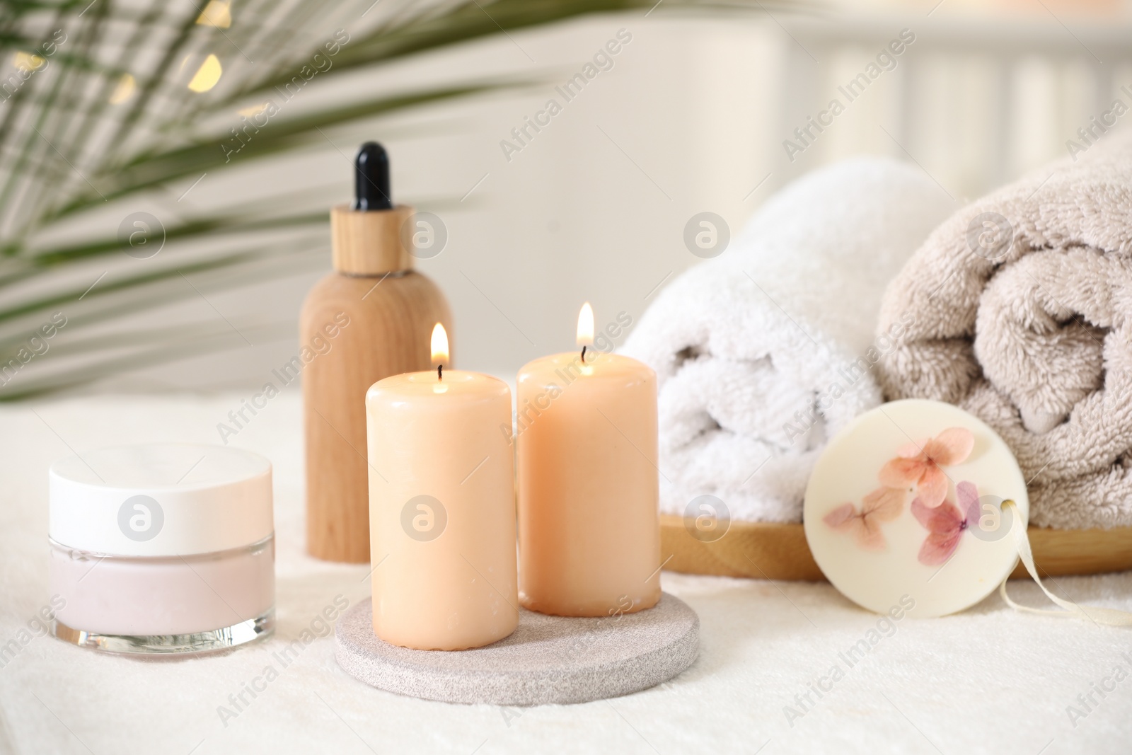 Photo of Spa composition. Burning candles and personal care products on soft white surface