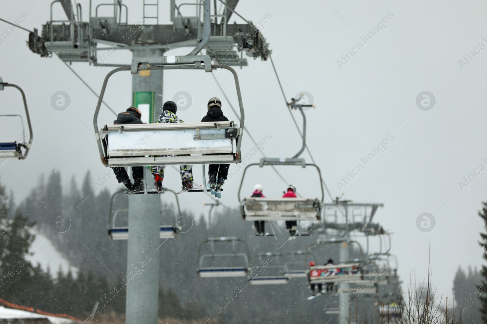 Photo of Chairlift with people at ski resort. Winter vacation