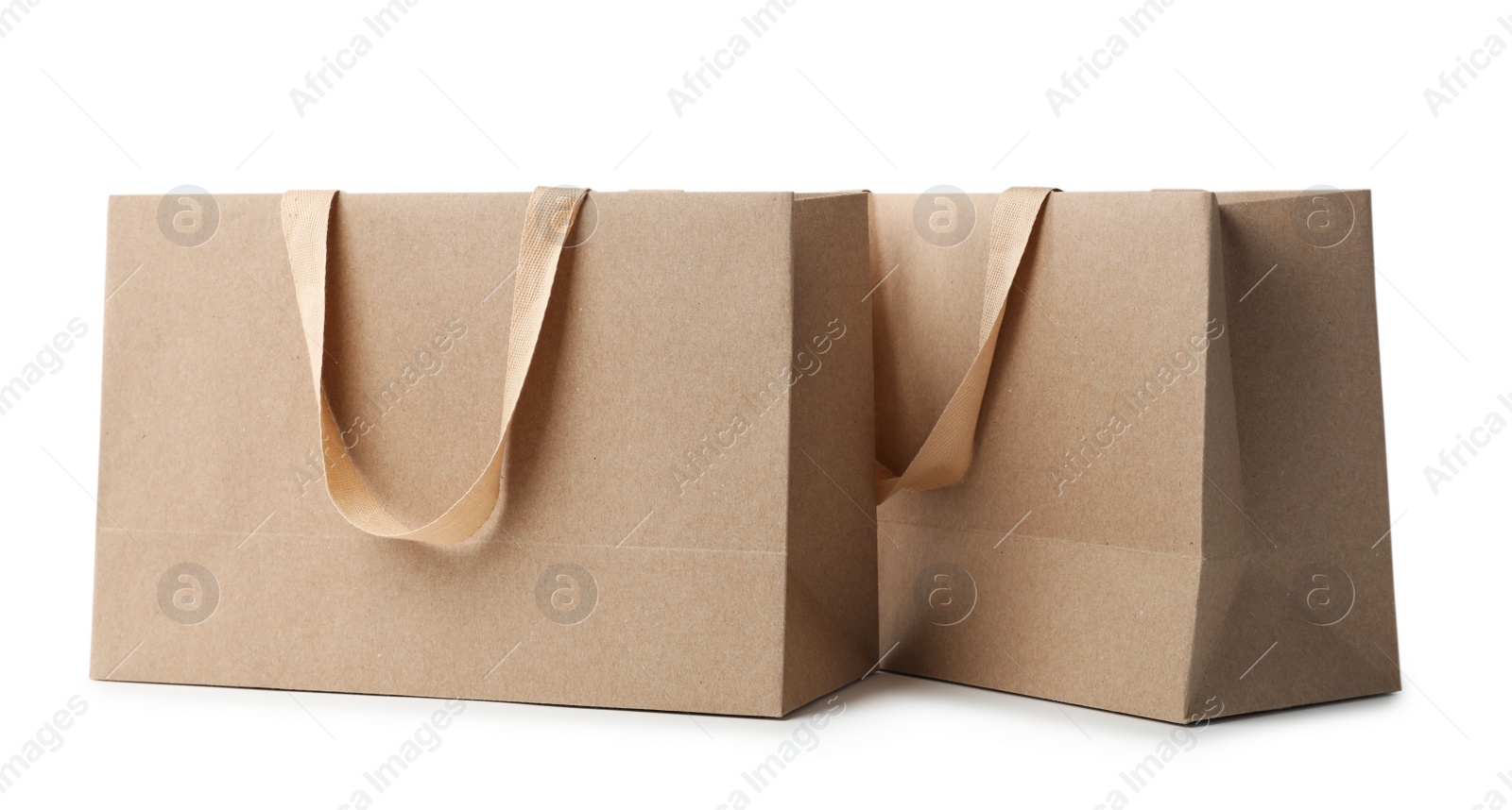 Photo of Paper shopping bags with comfortable handles on white background. Mockup for design