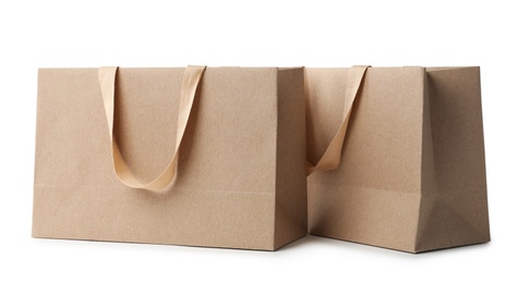 Photo of Paper shopping bags with comfortable handles on white background. Mockup for design