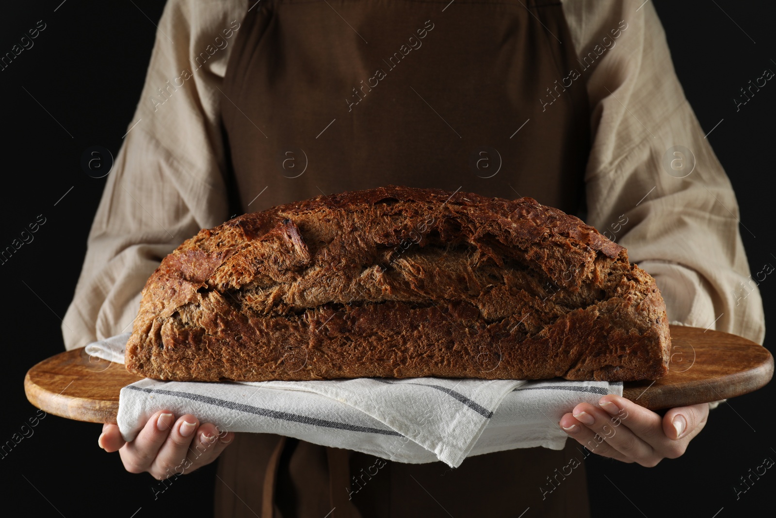 Photo of Woman holding freshly baked bread on black background, closeup