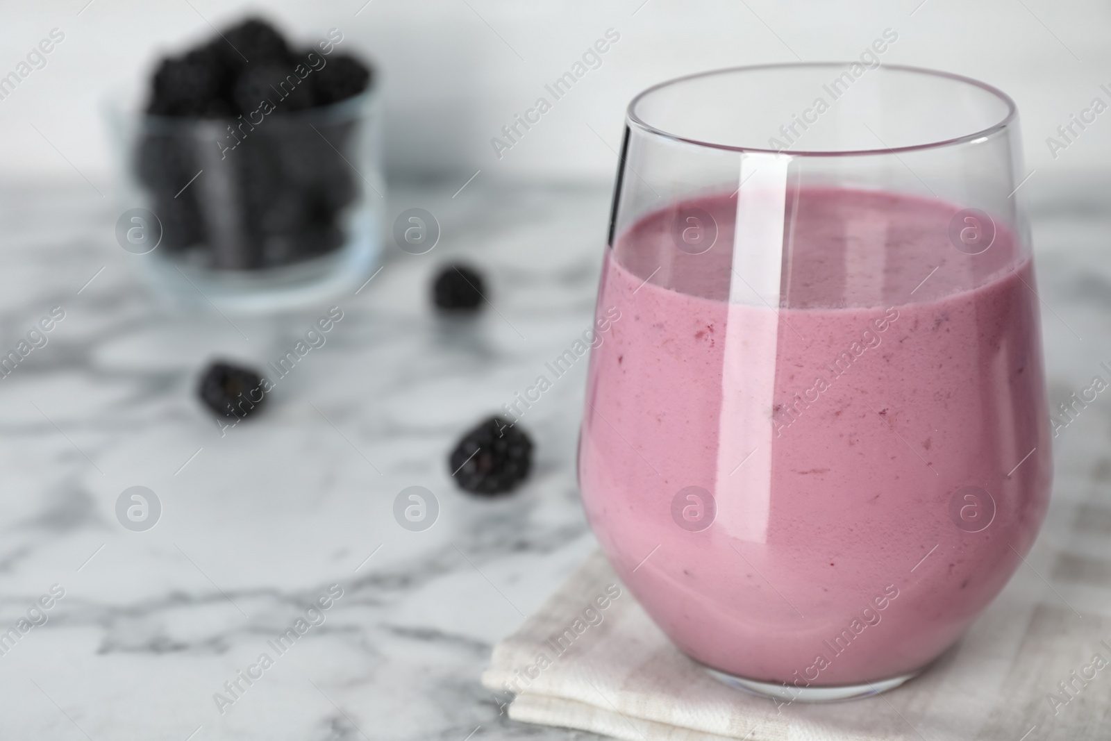 Photo of Glass with blackberry yogurt smoothie on marble table