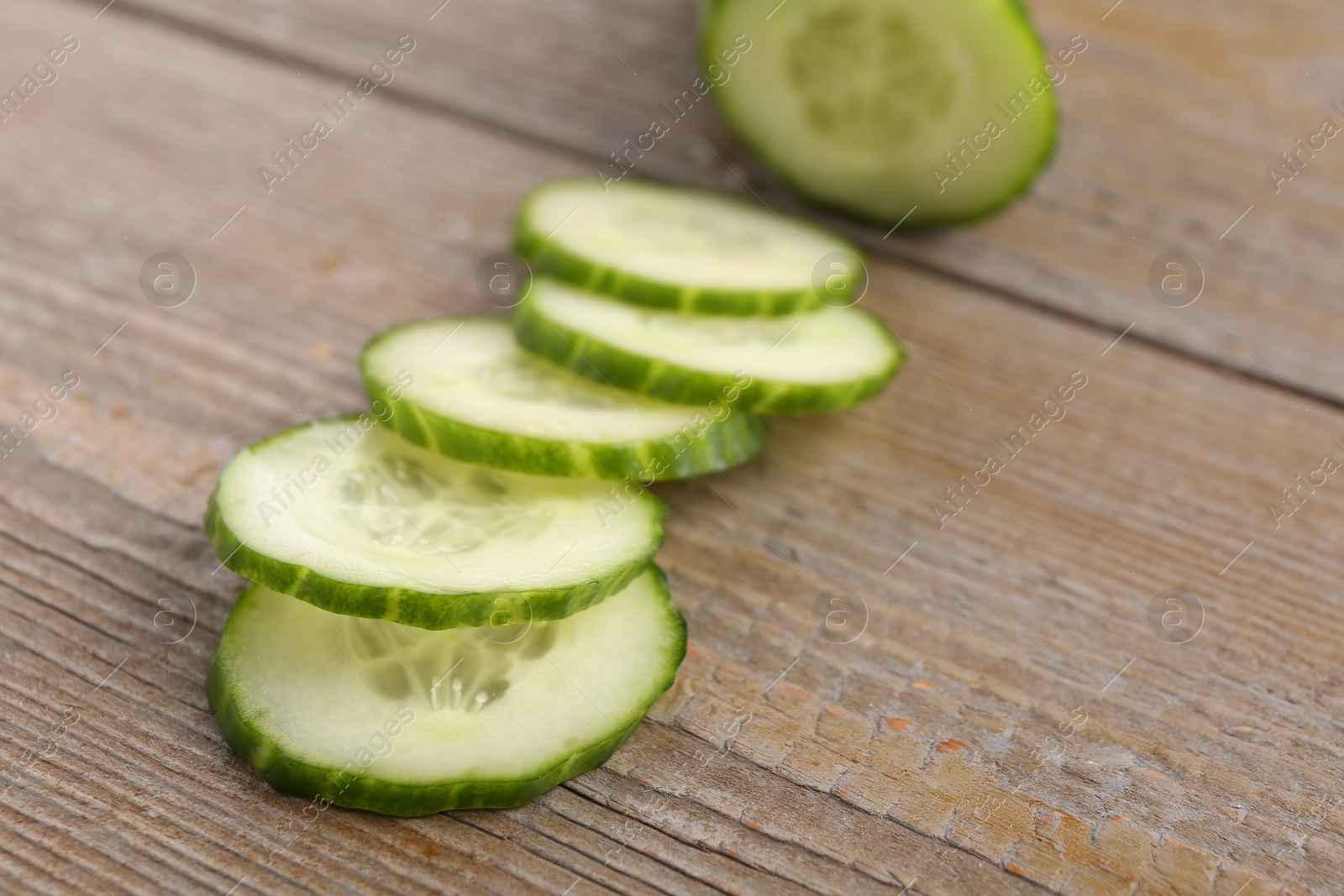 Photo of Cut ripe cucumber on wooden table, closeup