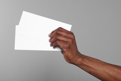 African American man holding flyers on grey background, closeup. Mockup for design